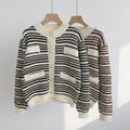 Black and white striped cardigan on a hanger against a neutral background