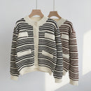 Black and white striped cardigan on a hanger against a neutral background